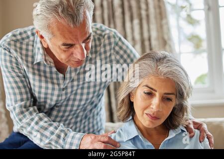 Reifer Mann beruhigend Frau mit Depressionen zu Hause Stockfoto