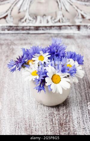 Bouquet von Kamillen und Kornblumen auf Holztisch. Einrichtung im Sommer Stockfoto