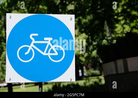 Zeichen des Fahrradparkplatzes auf dem Hintergrund der grünen Bäume im Park. Speicherplatz kopieren. Stockfoto