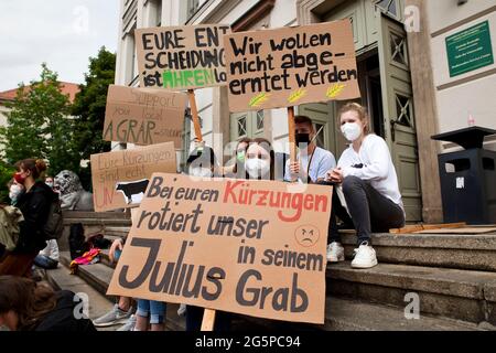 29. Juni 2021, Sachsen-Anhalt, Halle (Saale): Demonstranten sitzen mit ihren Plakaten vor der Martin-Luther-Universität. Bauern aus Sachsen-Anhalt und Studierende der Universität (MLU) demonstrieren gemeinsam gegen die Kürzungspläne der Universität, die auch das Departement für Agrarwissenschaft betreffen würden. Foto: Johannes Stein/dpa-Zentralbild/dpa Stockfoto