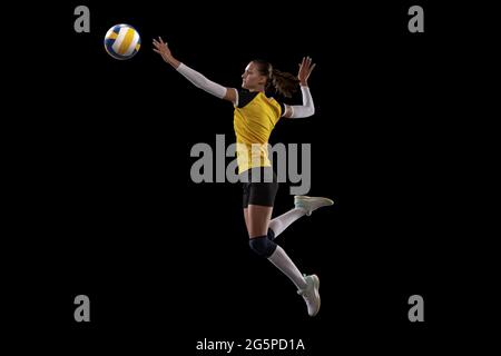 Weibliche professionelle Volleyballspielerin mit Ball isoliert auf schwarzem Studio-Hintergrund. Der Sportler, Bewegung, Aktion, Sport, gesunder Lebensstil, Schulungen Stockfoto