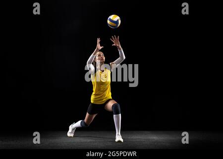 Weibliche professionelle Volleyballspielerin mit Ball isoliert auf schwarzem Studio-Hintergrund. Der Sportler, Bewegung, Aktion, Sport, gesunder Lebensstil, Schulungen Stockfoto