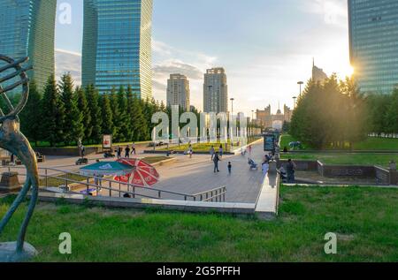 Nur-Sultan - Kasachstan: 10. Juni 2021: Zentrum von nur-Sultan mit Park, Wolkenkratzern auf dem Nurjol Boulevard, Menschen bei Sonnenuntergang im Sommer. Stockfoto