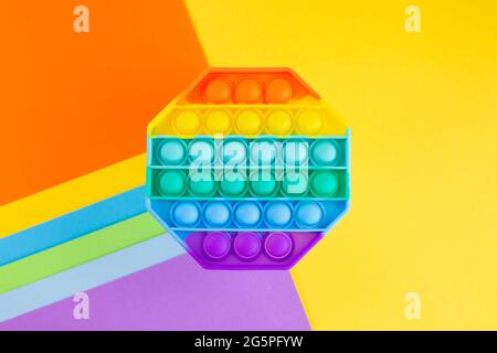 Antistress-Pop-it-Spielzeug. Rainbow Silikon sensorische Fidget auf farbivollem Hintergrund. Neue beliebte trendige Silikon-Spielzeug. Stockfoto