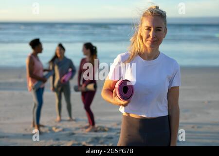 Porträt einer kaukasischen Frau, die Yoga praktiziert, am Strand steht und Pause macht Stockfoto