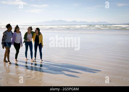 Glückliche Gruppe von verschiedenen Freundinnen, die Spaß haben, am Strand entlang laufen und die Hände halten und lachen Stockfoto