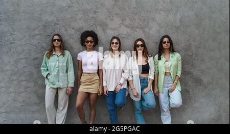 Portrait von fünf Mädchen, die auf einer Betonwand stehen, Spaß haben, Sonnenbrillen tragen und die Kamera beobachten. Millennials Mädchen nur Konzept. Stockfoto