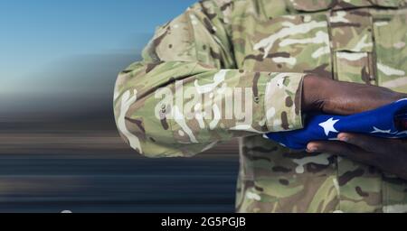 Zusammensetzung des Mittelteils des Soldaten mit Hand auf gefalteter amerikanischer Flagge Stockfoto