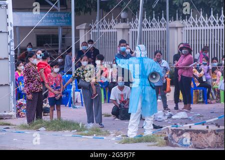 Phnom Penh, Kambodscha. 29. Juni 2021. Seit 4 Monaten kämpft Phnom Penh gegen einen COVID - 19-Anstieg. Ein EMT in voller PSA leitet eine Massenteststelle. Eine kambodschanische Mutter und ihre zwei kleinen Jungen haben alle positiv auf das Virus getestet und werden von einem Krankenwagen abgeholt. Kraig Lieb / Alamy Live News Stockfoto