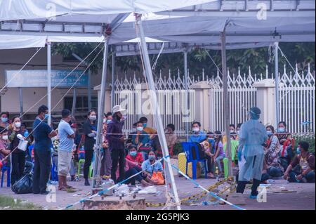 Phnom Penh, Kambodscha. 29. Juni 2021. Seit 4 Monaten kämpft Phnom Penh mit einem COVID - 19-Anstieg. Ein EMT in voller persönlicher Schutzausrüstung leitet eine Massenteststelle. Eine Gruppe Kambodschaner, die alle positiv auf das Virus getestet haben, warten darauf, von Krankenwagen abgeholt zu werden. Quelle: Kraig Lieb / Alamy Live News Stockfoto