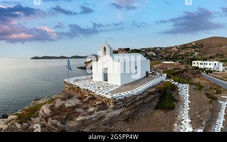 Agios Georgios Kapelle auf einem felsigen Hügel im Hafen von Korissia, Insel Kea Tzia. Griechenland, Kykladen. Luftdrohnenansicht. Geriffeltes Meer, blauer wolkig Himmel. Sommer vac Stockfoto