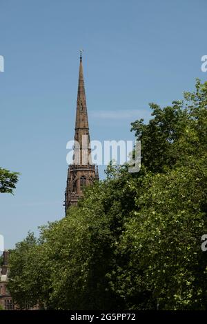 Der Turm der Kathedrale von Coventry unter Bäumen, auch bekannt als St. Michaels, eine gotische Kirche aus dem 14. Jahrhundert, am 23. Juni 2021 in Coventry, Großbritannien. Die Cathedral Church of Saint Michael, allgemein bekannt als Coventry Cathedral, ist der Sitz des Bischofs von Coventry und der Diözese Coventry innerhalb der Church of England. Die Kathedrale liegt in Trümmern und bleibt nach den Bombenangriffen im Zweiten Weltkrieg eine zerstörte Muschel. Stockfoto