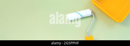 Neue Malrolle und gelbes Farbtablett auf pastellgrünem Hintergrund, Webbanner Stockfoto
