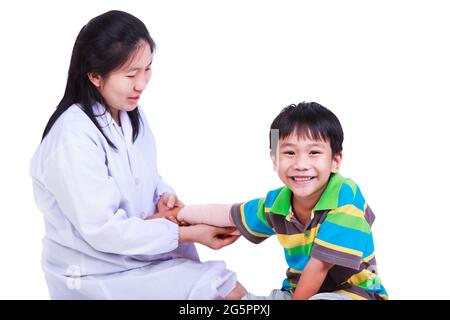 Konzept Foto von Kindern Gesundheit und medizinische Versorgung. Der Arzt gibt erste Hilfe bei der Verbandserscheinungen beim Armtrauma des Patienten. Studioaufnahme. Isoliert auf weißem Hintergrund Stockfoto