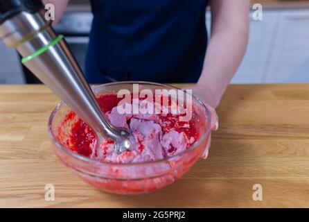 Eiscreme-Garvorgang aus Erdbeeren und Joghurt in einer Schüssel mit einem Mixer Stockfoto