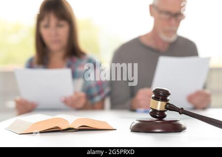 Scheidungskonzept mit Richtergavel und paar Lesestoff im Hintergrund, Fokus auf den Vordergrund Stockfoto