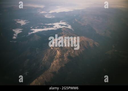 Panoramablick auf die asiatischen Berge bei Sonnenaufgang vom Flugzeug aus Stockfoto