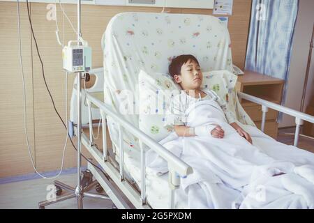 Krankheit asiatisches Kind im Krankenhaus mit Infusionspumpe intravenösem i.v. Tropf eingeliefert. Gesundheitsfürsorge und medizinisches Konzept. Vintage-Style. Stockfoto