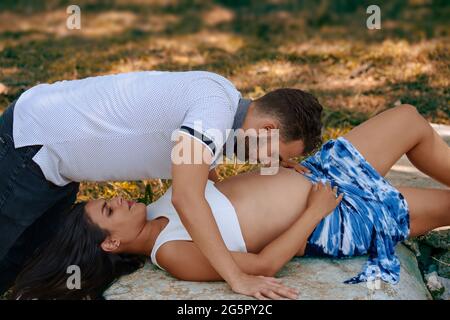 Foto einer jungen Schwangeren, die auf ihrem Rücken auf einem Felsen liegt und eines jungen Mannes auf ihr Stockfoto