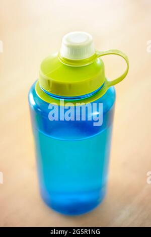 Blaue Wasserflasche auf dem Tisch für Fitness und Hydratation mit Frischwasser-Quench dursd Stockfoto