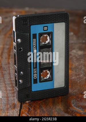 Das Audiotape ist in einem klassischen schwarzen Maxell-Gehäuse eingerahmt, das auf einem braunen Holzhintergrund steht. Draufsicht von der Seite Stockfoto