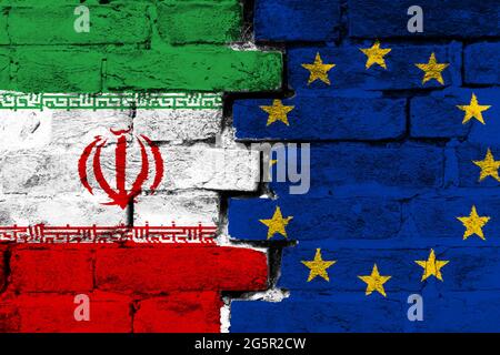 Konzept des Verhältnisses zwischen dem Iran und der Europäischen Union mit zwei bemalten Fahnen auf einer beschädigten Ziegelmauer Stockfoto