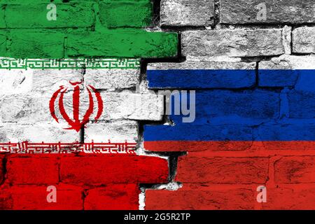 Konzept des Verhältnisses zwischen Iran und Russland mit zwei bemalten Fahnen auf einer beschädigten Ziegelmauer Stockfoto