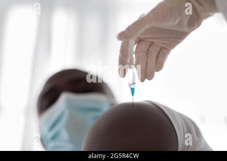 Professioneller Arzt oder Krankenschwester in Gummihandschuhen für Erwachsene, die dem Patienten eine Grippe- oder COVID-19-Injektion verabreichung verabreichung Stockfoto