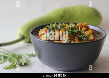 Flasche Curry mit Linsen. Ein Topf Kichererbsen Linsengericht mit einer Flasche Kürbiszwiebeln Tomaten und Gewürzen gekocht. Aufgenommen auf weißem Hintergrund. Stockfoto