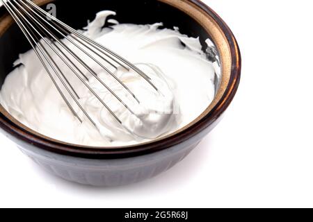 Schlagsahne mit einem Schneebesen auf weißem Hintergrund Stockfoto