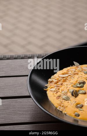 Vertikale Aufnahme der Kürbiscremesuppe mit verschiedenen Nüssen darauf. Stockfoto