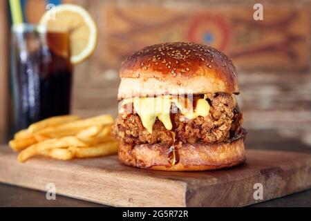 Köstliche hausgemachte knusprige Chicken Burger auf Holztablett mit Cola und Feuer. Nahaufnahme von natürlichem Licht. Stockfoto