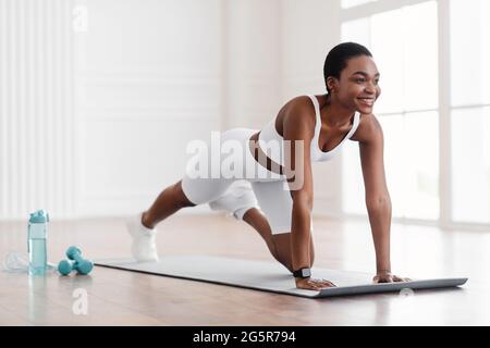 Afro-Fröhliche Frau, Die Die Übung Von Cross Body Mountain Kletterern Macht Stockfoto