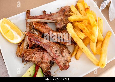 Gegrillte Lammrippchen mit Pommes Frites im Restaurant. Traditionelles griechisches Gericht. Stockfoto