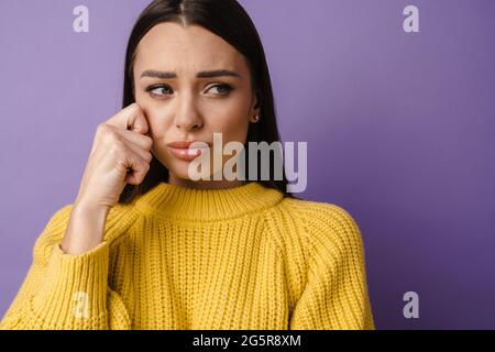 Porträt von unzufrieden aufgeregt weiblichen Stirnrunzeln Gesicht als zu weinen isoliert über violetten Hintergrund. Enttäuscht hat eine junge Frau Probleme Stockfoto