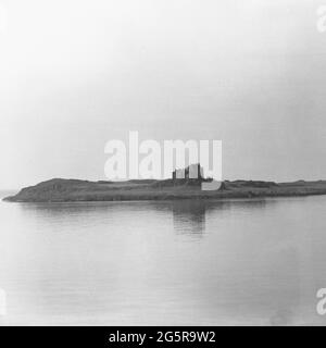 1950er Uhr, historischer Blick auf Ruinen auf einem Stück tiefem Land neben den ruhigen, ruhigen Gewässern von A loch, Socttish Highlands, Schottland, Großbritannien. Stockfoto