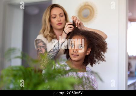 Mutter stylen die Haare der Tochter zu Hause Stockfoto