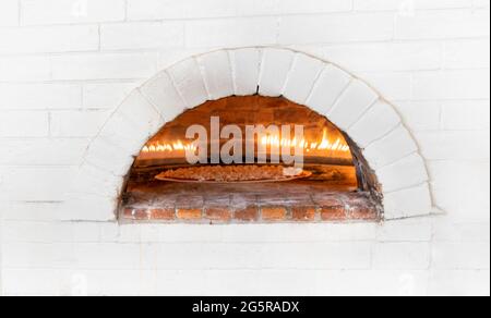 Pizzen oder Pita Brot backen und kochen in offenem Brennholz typischen Backstein weißen Ofen Stockfoto
