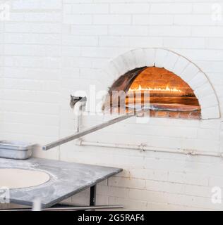Pizzen oder Pita Brot backen und kochen in offenem Brennholz typischen Backstein weißen Ofen Stockfoto