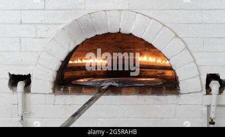 Pizzen oder Pita Brot backen und kochen in offenem Brennholz typischen Backstein weißen Ofen Stockfoto