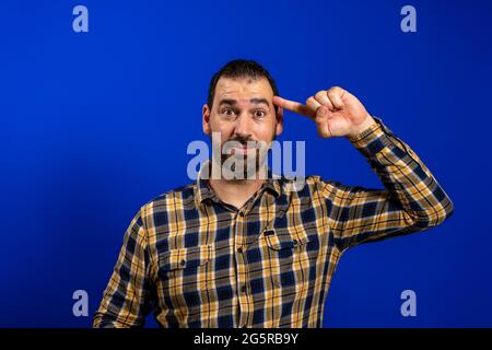 Hübscher Mann mittleren Alters über isoliertem blauen Hintergrund lächelnd mit einem Finger auf den Kopf zeigend, tolle Idee oder Gedanke, gutes Gedächtnis. Stockfoto
