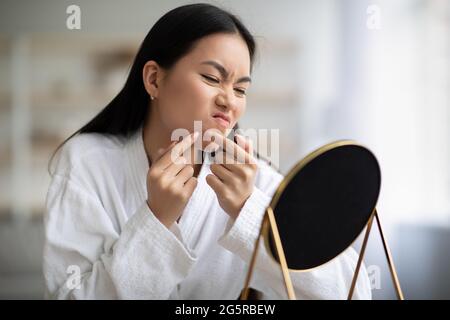 Junge asiatische Dame im Bademantel entfernt schwarze Köpfe Stockfoto