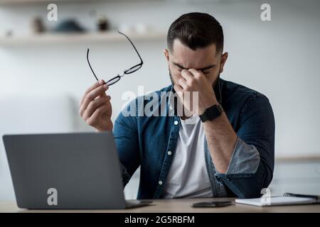 Müde junge männliche Gefühl Schmerzen Augenbelastung halten Brille, reiben trocken reizte Augen Stockfoto