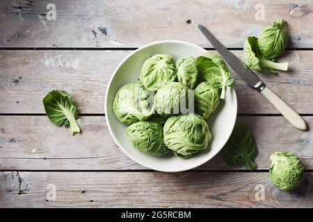 Frisches grünes Brüssel sprießt in einer Schüssel auf einem Holztisch, Draufsicht. Stockfoto