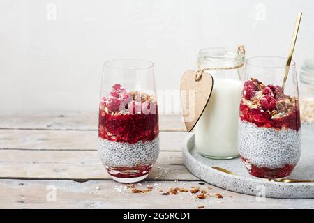 Zwei Gläser Chia Pudding mit Müsli und Himbeeren. Stockfoto