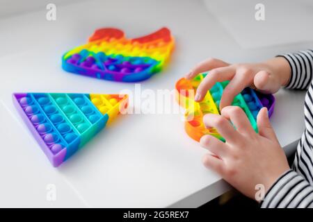 Mädchen sitzt an einem Tisch und spielt Spielzeug Pop it. Drinnen Stockfoto