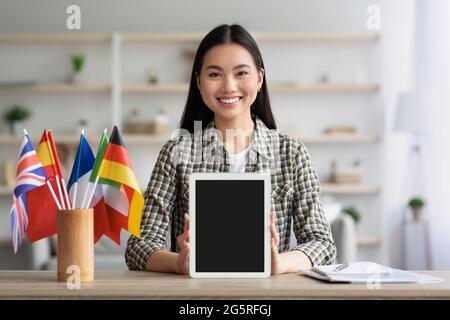 Glückliche asiatische Frau zeigt digitale Tablette mit leerem Bildschirm Stockfoto