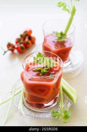 Tomatensaft in einem Glas, mit Petersilie und Sellerie-Sticks verziert. Stockfoto