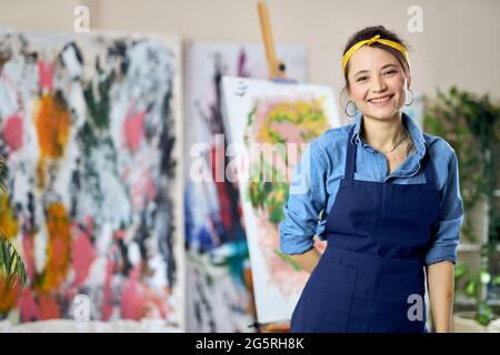 Glückliche junge Frau, Künstlerin in Schürze lächelnd an der Kamera, posiert zu Hause Studio-Werkstatt Stockfoto