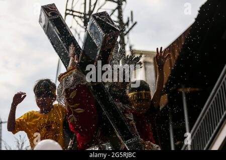 Philippinisch-katholische Anhänger heben ihre Hände und Handtücher, während Priester vor dem Fest des Schwarzen Nazareners in Manila, Philippinen, Heiliges Wasser auf die Repliken des Schwarzen Nazareners streuen. Stockfoto